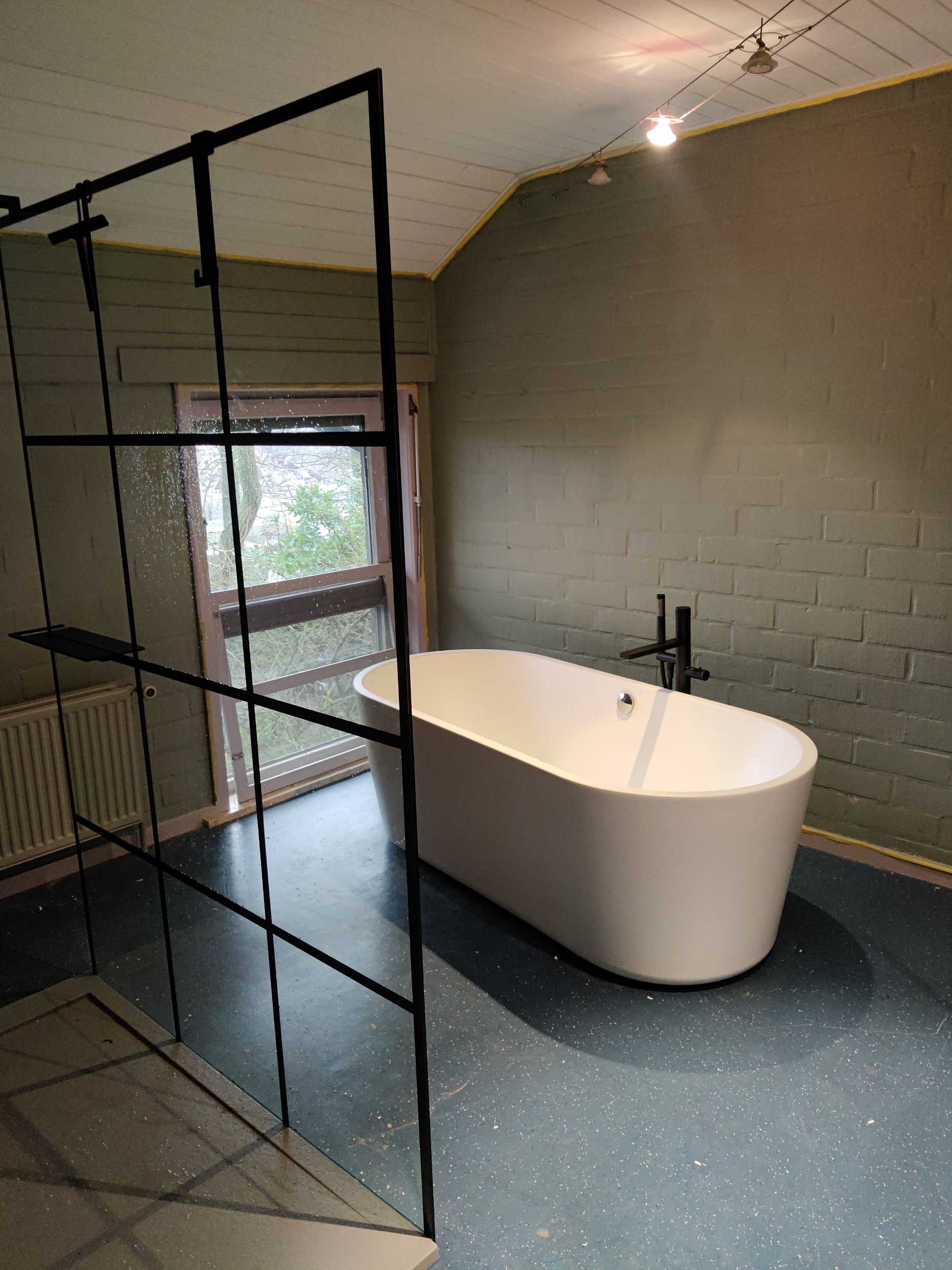 Badkamer met vrijstaand bad en stalen glaswand door DEWA Sanitair