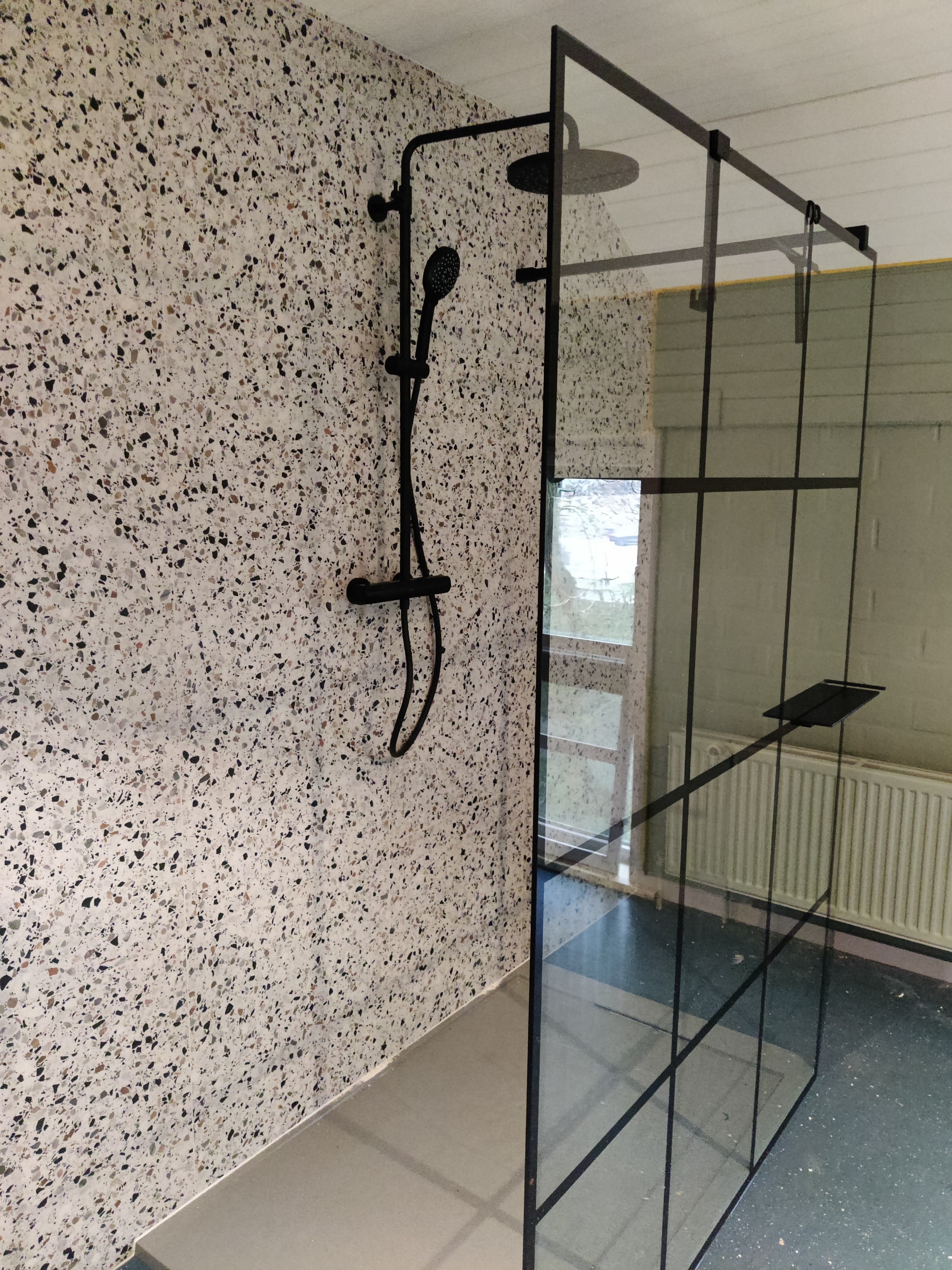 Inloopdouche met terrazzo-wand en zwarte regendouche